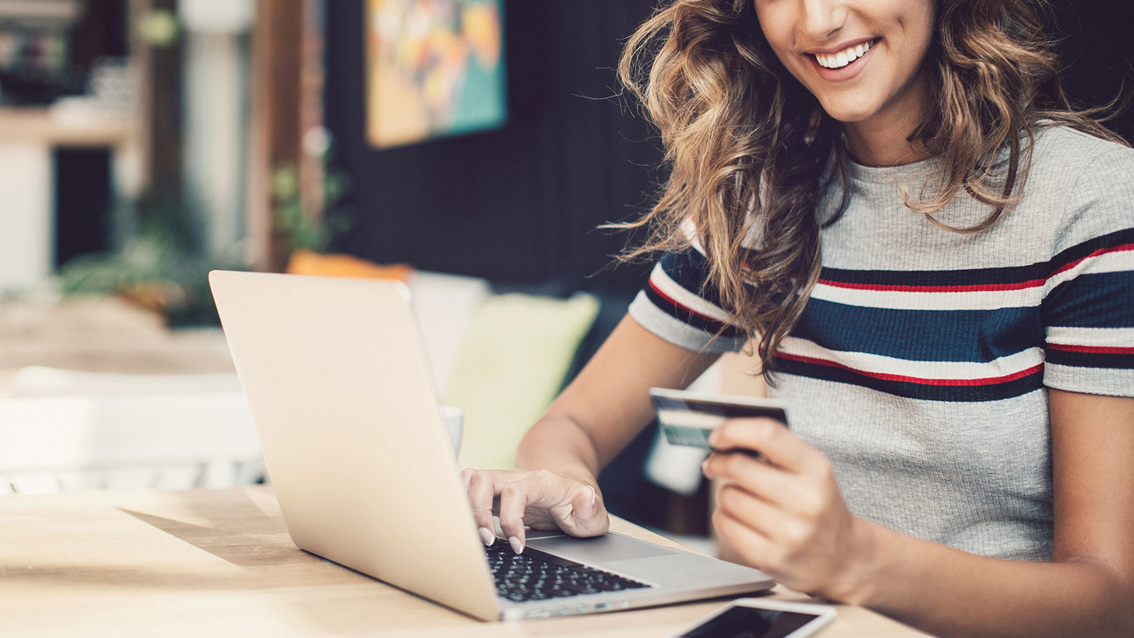 Woman at her computer looking on the computer with credit card