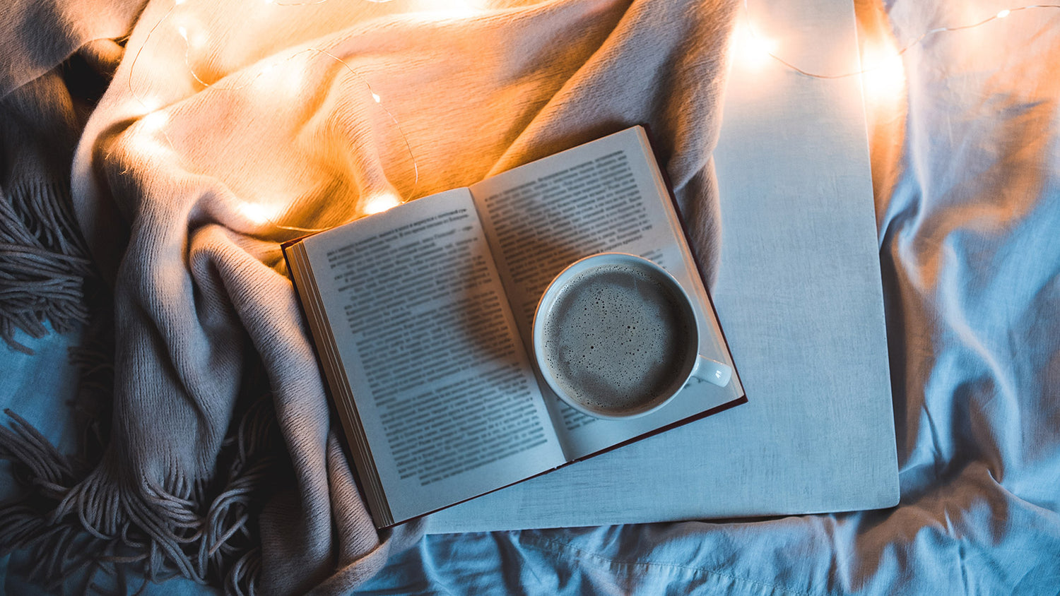 Person prepping for their evening bedtime routine by winding down with a hot beverage and reading a relaxing book.