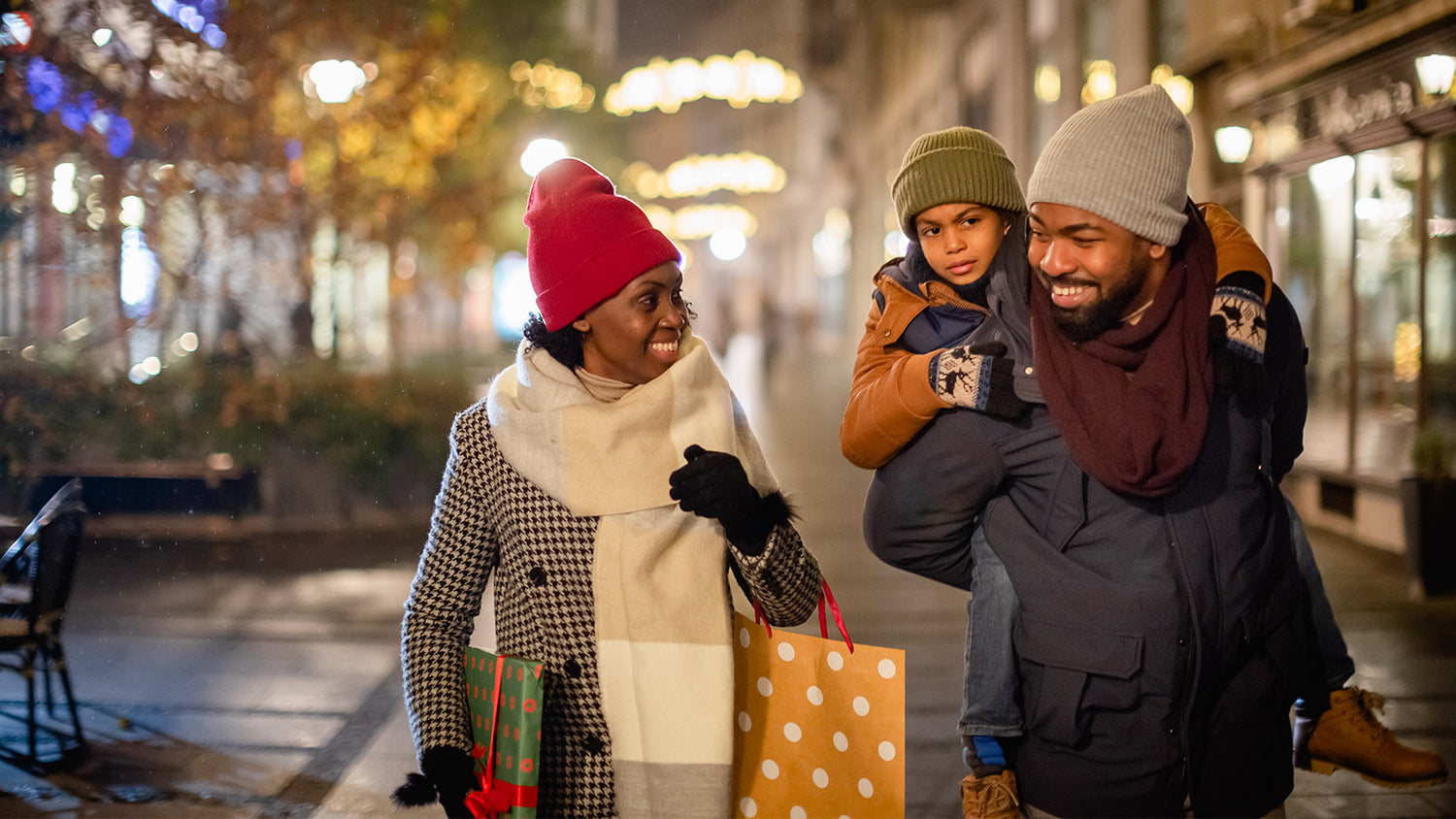 Black Mother Father and Son walking through town at night shopping and engaging with each other