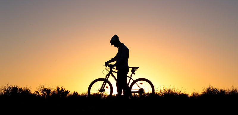 Josh Quigley standing next to his bike in front of a sunrise